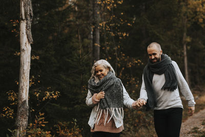 Man and woman standing on land against trees