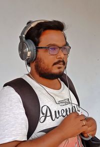 Portrait of young man wearing eyeglasses against wall