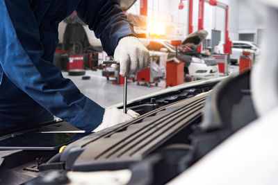 Midsection of mechanic repairing car