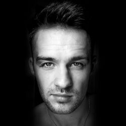 Portrait of young man against black background