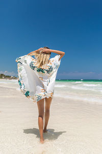 Portrait of woman at beach against clear blue sky