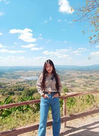 Portrait of smiling young woman standing against sky