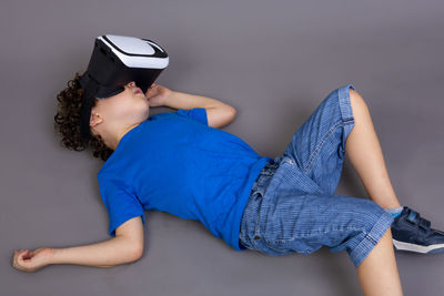 Photo of child playing with virtual reality glasses. lying on the ground