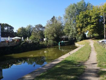 Footpath by canal against sky