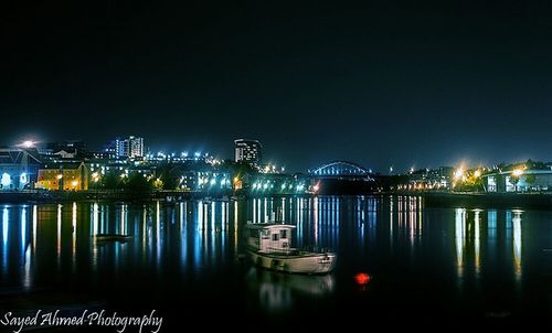 Illuminated bridge over river at night