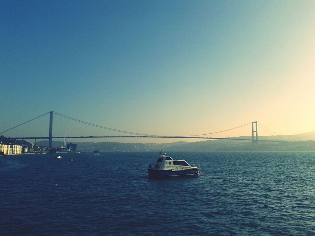 connection, bridge - man made structure, transportation, water, suspension bridge, engineering, sea, waterfront, built structure, bridge, clear sky, architecture, copy space, river, travel destinations, travel, rippled, nautical vessel, sky, tranquil scene