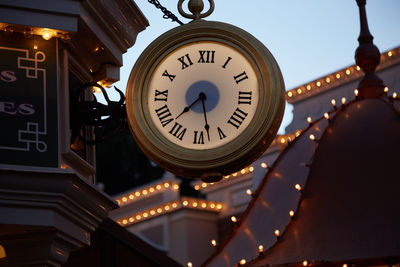 Low angle view of illuminated clock hanging