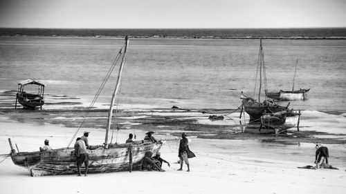 People working on beach against sky