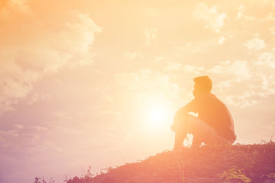 Silhouette man standing on rock against sky during sunset