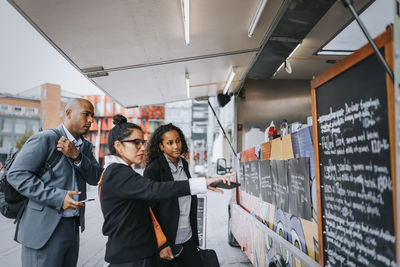 Male and female corporate professionals ordering food from food truck