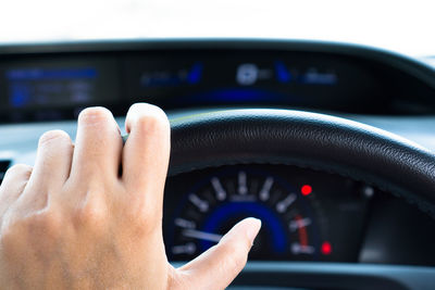 Close-up of human hand on steering wheel 