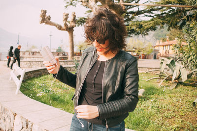 Woman using mobile phone while standing at park