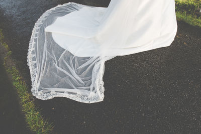 Low section of bride wearing wedding dress on road