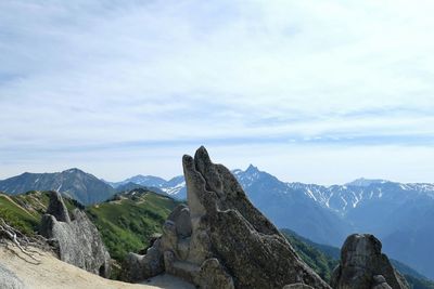 Rock by mountain against sky in background