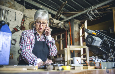 Senior woman talking over mobile phone in workshop