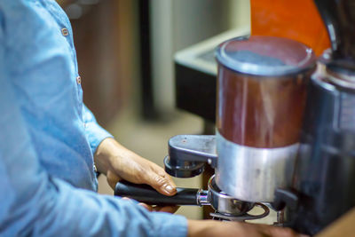 Close up barista is grinding freshly roasted by coffee grinder make beans into a powder.