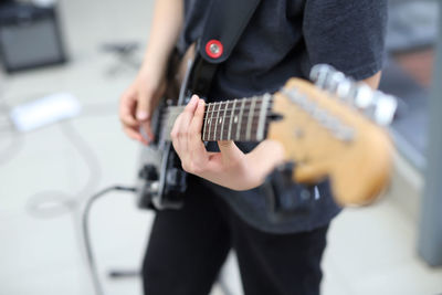 Midsection of man playing guitar