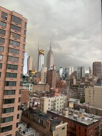 Buildings in city against cloudy sky