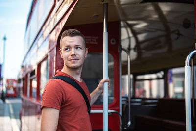 Portrait of tourist boarding to red double-decker bus in central london. united kingdom.