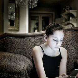 Girl using phone while sitting on sofa in living room at home