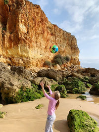 Full length of woman on rock at beach against sky