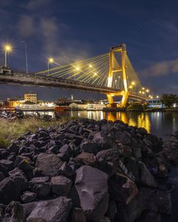 Illuminated bridge over river against sky