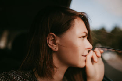Blurry image of beautiful young woman looking thoughtfully out of an open car window