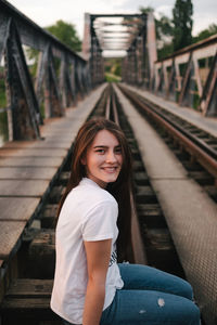 Portrait of smiling young woman on railroad tracks