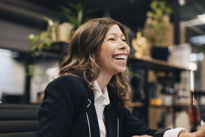 Cheerful businesswoman looking away at creative office