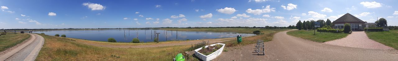 Panoramic view of road by canal against sky