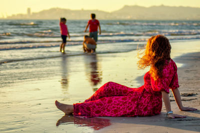 Rear view of women sitting on beach