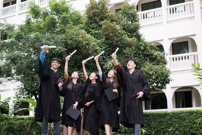 Students in university gowns standing against building