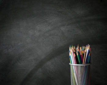 Colorful colored pencils in desk organizer against black wall