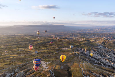 Hot air balloons flying over landscape against sky