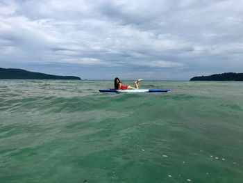 People on boat in sea against sky