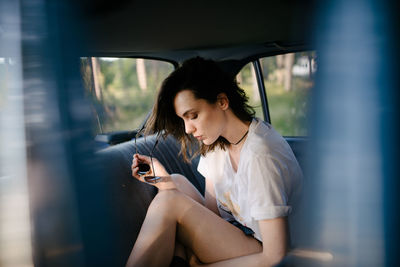 Portrait of a hipster woman in the back seat of a car.