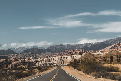 Road leading towards mountains against sky