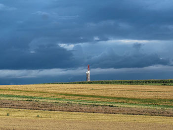 Lighthouse on field against sky