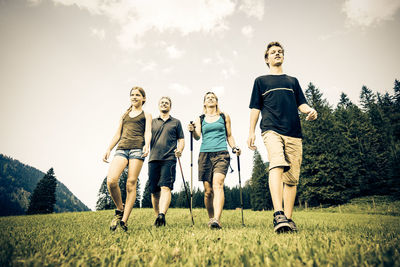 Low angle view of people standing on soccer field against sky