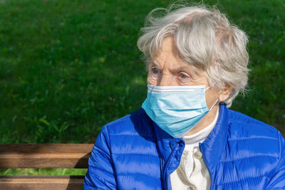 Senior woman wearing mask sitting outdoors