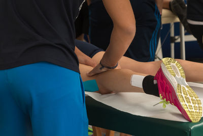 Midsection of man giving massage to athlete lying on bed