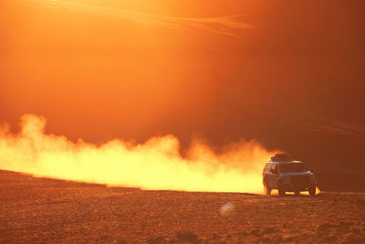 Rear view of fire on sea at sunset