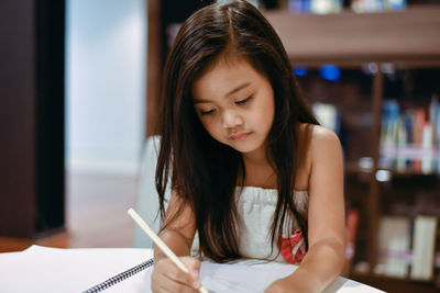 Girl looking away while sitting on book