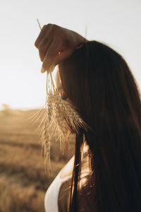 Woman holding wheat crop at farm at sunset