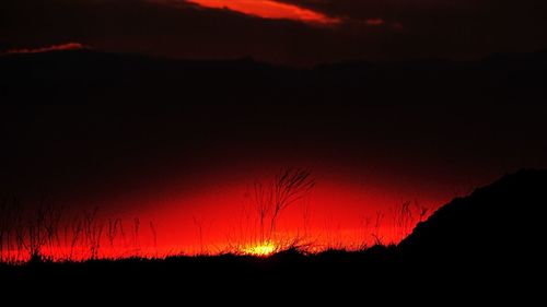 Silhouette landscape against sky at sunset