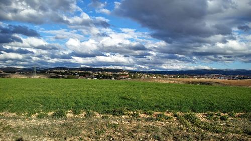 Scenic view of grassy field against cloudy sky