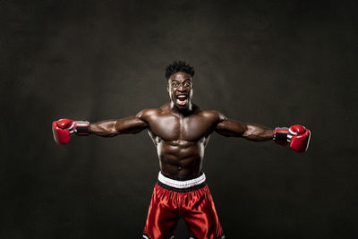 Portrait of shirtless boxer standing against black background