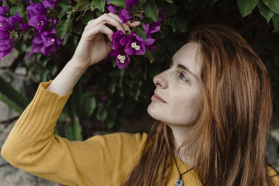 Spain, canary islands, fuerteventura, profile of redheaded young woman with purple blossoms