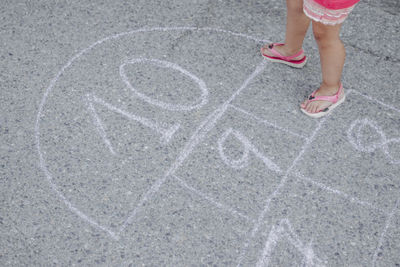 Low section of girl playing hopscotch on street