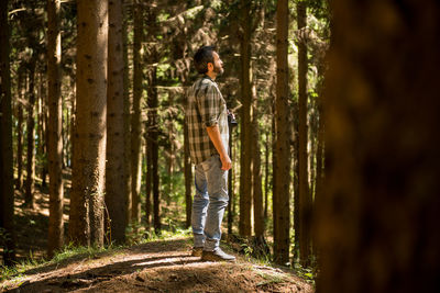 Woman standing on tree trunk in forest